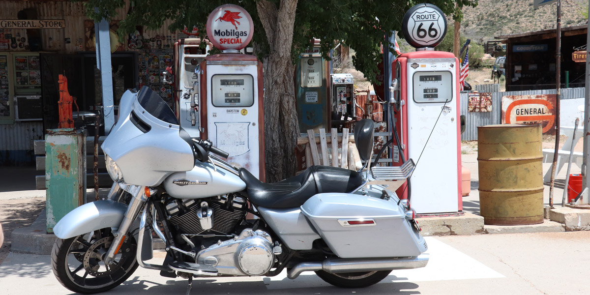 Une moto, sur la route 66 devant deux anciennes pompes à essence